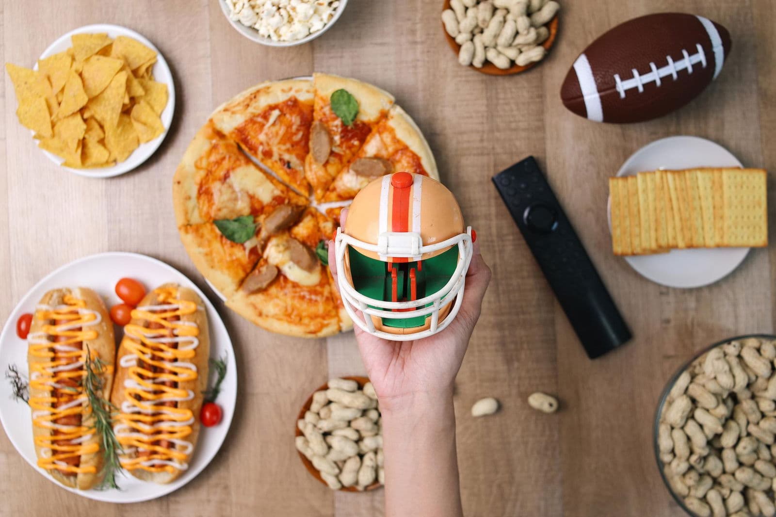 High angle of hands holding little rugby helmet and snacks for watching sports game