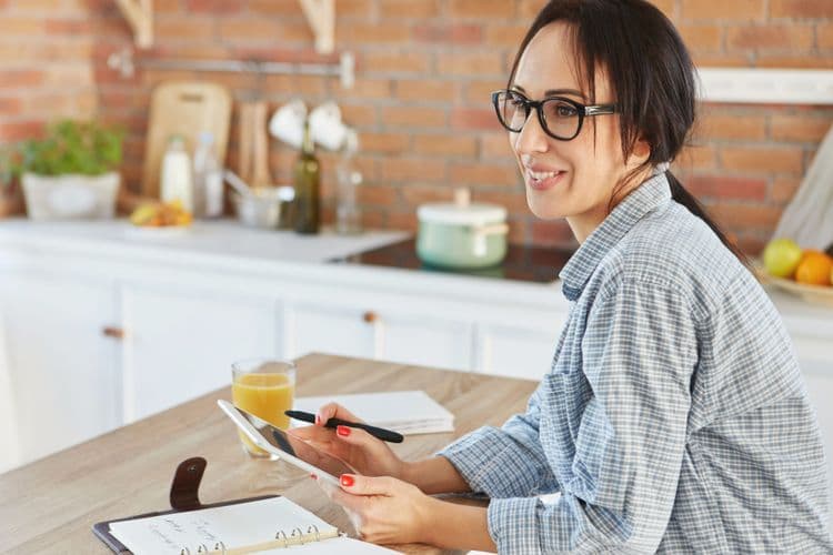 Home cook using a tablet in a cozy kitchen to plan SEO-friendly recipes with Chefadora’s Recipe Genie